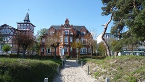 Un grand bâtiment historique, doté d’une tour imposante et d’un jardin bien entretenu, avec un chemin menant à l’entrée.