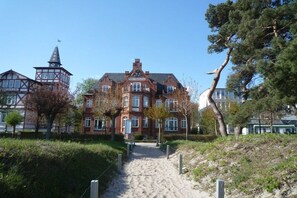 Suuri, historiallinen rakennus, jossa on huomiota herättävä torni ja hyvin hoidettu puutarhapolku, joka johtaa sisäänkäynnille.