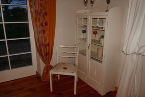 A room with a white cabinet, a chair, and a window with curtains. - Holiday home with 2 bedrooms (Saal OT Neuendorf Heide)