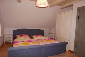 A bedroom with a bed, bedside tables, a wardrobe, and a hanging light fixture. - Holiday home with 2 bedrooms (Saal OT Neuendorf Heide)