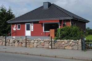 Ein rotes Gebäude mit einem weißen Anker-Symbol, einer Steinmauer und einem Metallzaun.