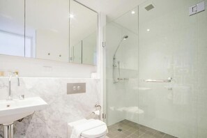 A modern bathroom with a glass shower enclosure, a white toilet, and a marble sink. - Accommodate Canberra Realm (Canberra)