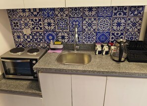 A kitchen with a microwave, stove, sink, and various kitchen items.