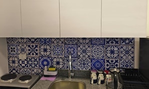 A kitchen with a sink, stove, and various kitchen items.