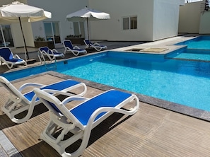 A pool area with lounge chairs and umbrellas.