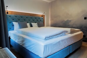A modern bedroom with a large bed, a tufted headboard, and a wall-mounted lamp. - Kehlstein Apartment, 55 square meters, for 2–4 people (Berchtesgaden)