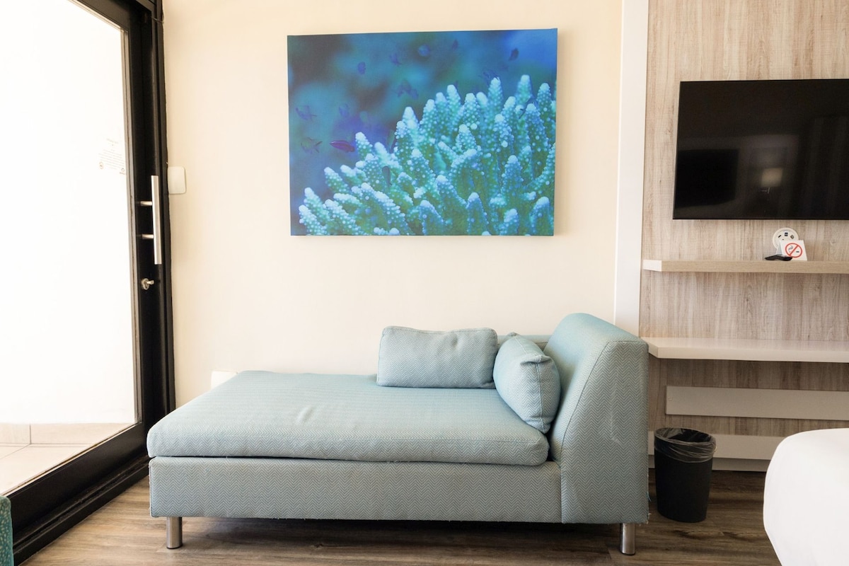 A modern living room with a sofa, a television mounted on the wall, and a window.