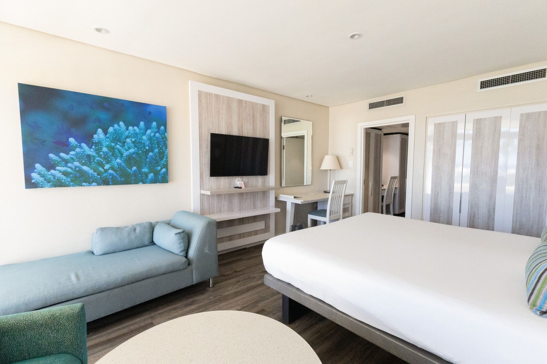 Habitación de hotel con cama, zona de estar, escritorio, televisión y baño.