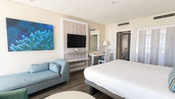Habitación de hotel con cama, zona de estar, escritorio, televisión y baño.