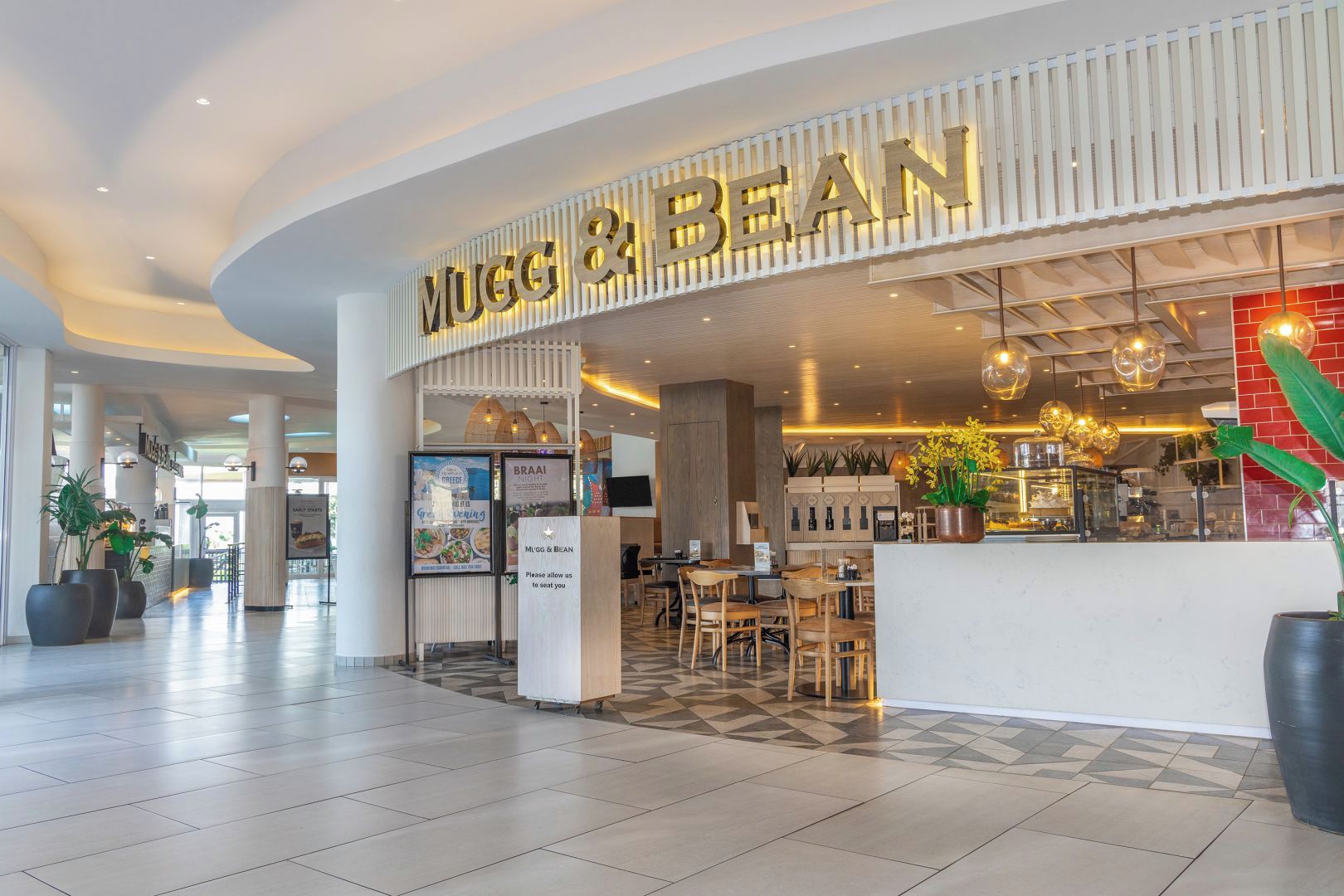 Un restaurante MUGG & BEAN con un interior moderno, zona de estar y mostrador.