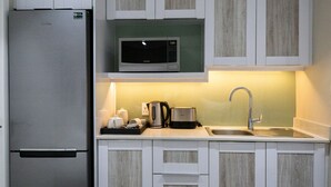 Eine kleine Küche mit einem Edelstahlkühlschrank, einer Mikrowelle, einem Wasserkocher, einem Toaster und einem Spülbecken.