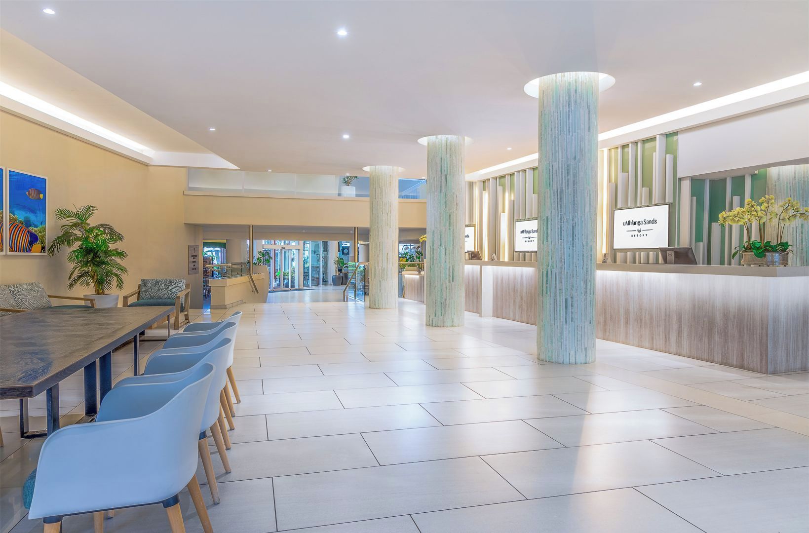 Un hall de hotel con recepción, zona de estar y vista al acceso.