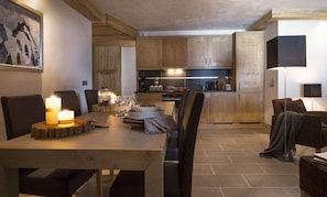 Una cocina moderna con armarios de madera, una mesa de comedor lista para cuatro personas y un rincón de estar acogedor con una lámpara.