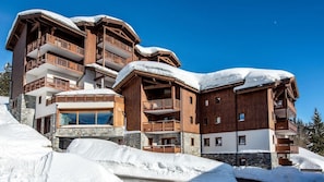 Un edificio de madera de varios pisos con balcones, rodeado de nieve.