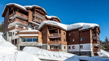 A multi-story wooden building with balconies, surrounded by snow.