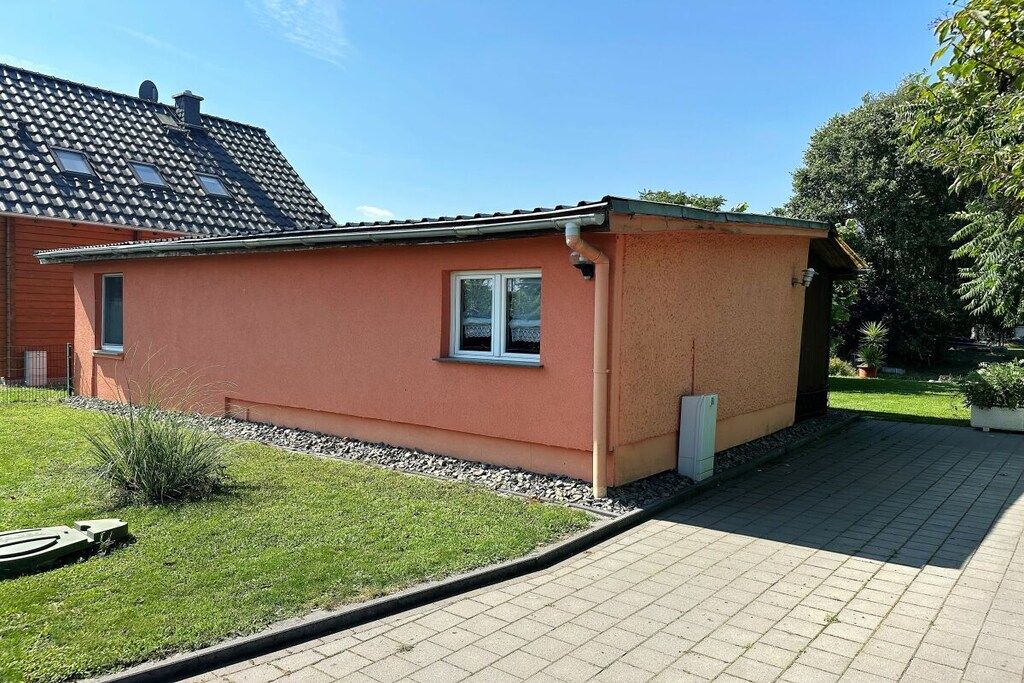 Une maison de plain-pied avec un toit en tuiles, un petit garage attenant et une allée pavée.