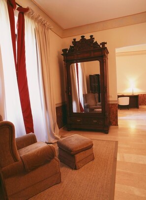 A room with a large mirror, a brown armchair, a small ottoman, and a chair.