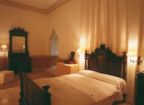 Ett hotellrum med en säng, ett sängbord, en spegel och en lampa.