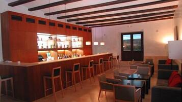 Un área de bar con sillas y mesas de madera, una barra con botellas y una vista a través de una puerta.