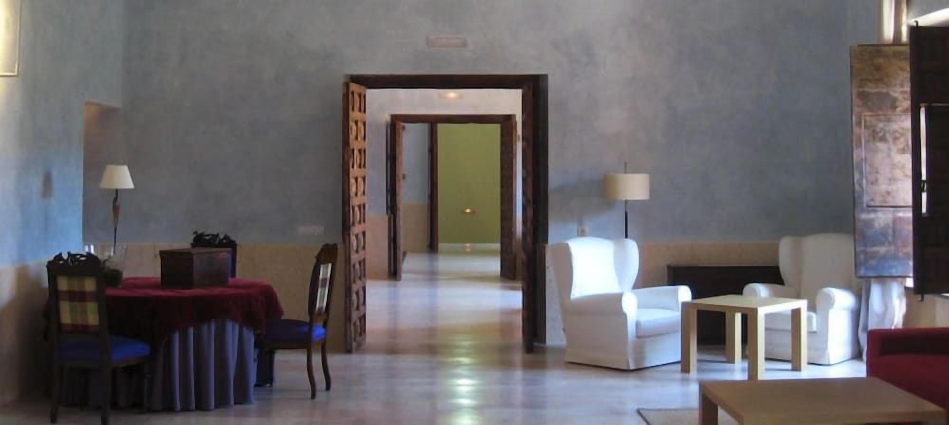 Hall d'albergo con area ristorazione, posti a sedere e un corridoio che porta in un'altra stanza.