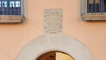 An arched entrance with a stone facade, a door, and a window with a geometric pattern.