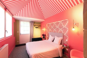 Quarto com cama, mesa de cabeceira, luminária na parede e janela com cortinas.