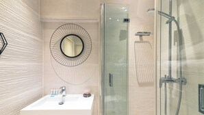 Een moderne badkamer met een douchecabine van glas, een ronde spiegel en een wit wastafelmeubel met toiletartikelen.