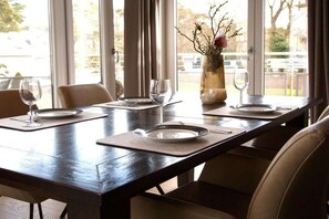 A dining table set with plates, cutlery, and wine glasses, with a vase of branches and a candle on the table. - Residence by the sea - Strandallee 178 (Timmendorfer Strand)
