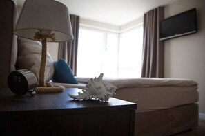 A hotel room with a bed, a bedside lamp, a decorative shell, and a television mounted on the wall. - Residence by the sea - Strandallee 178 (Timmendorfer Strand)