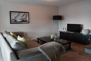 A modern living room with a sofa, coffee table, and a flat-screen TV. - Residence by the sea - Strandallee 178 (Timmendorfer Strand)