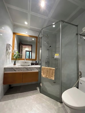 Un baño moderno con ducha envuelta en vidrio, un lavabo blanco y un inodoro.