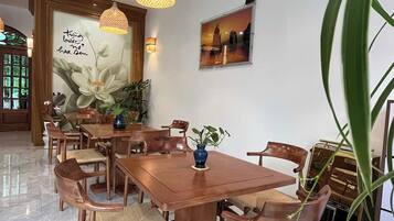 Un comedor con una mesa y sillas de madera, lámparas colgantes y una pared con un mural floral.