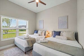 A hotel room with two beds, a ceiling fan, and a view of the outdoors. - Palms on 45th | Gulf Access, Heated Pool & Spa (Cape Coral)