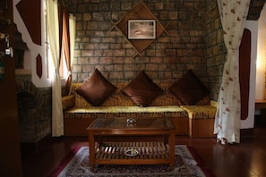 Una habitación acogedora con un sofá frente a una pared de ladrillo, una pequeña mesa de centro de madera y una alfombra estampada.