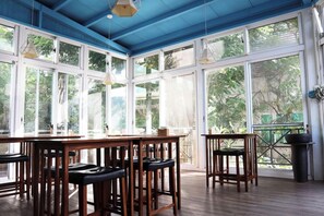 Una habitación con ventanas amplias, una mesa de madera y taburetes de bar.