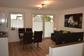 A compact living space with a kitchenette, dining area, and a sofa with a TV. - Dinius Schützenstraße (Grömitz)