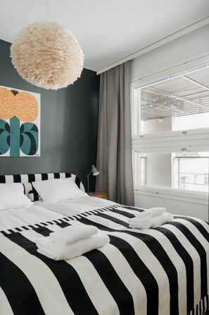 Ein modernes Schlafzimmer mit einem großen Bett, einer Pendelleuchte und einem Fenster mit Blick.