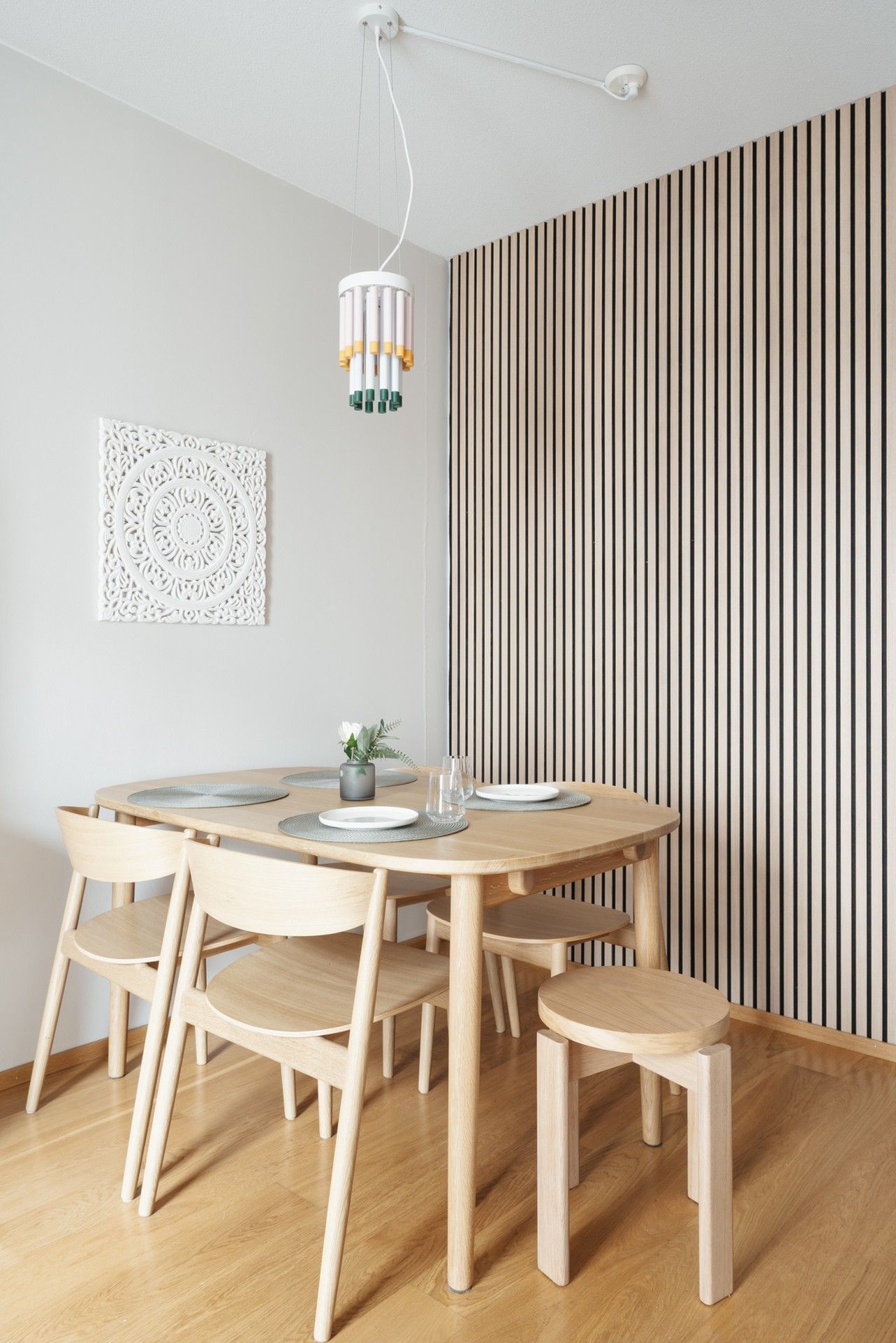 Un espace repas moderne avec une table ronde en bois, des chaises assorties et un luminaire suspendu.
