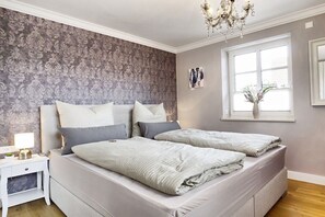 Ein Schlafzimmer mit einem Doppelbett, einem Nachttisch, einer Lampe, einem Fenster mit Blick und einer Chandelier.