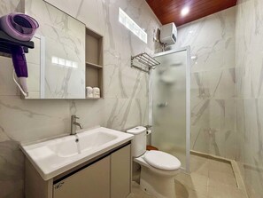 A bathroom with a white sink, toilet, and glass shower enclosure.