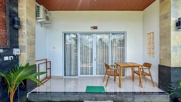 A modern outdoor patio with a wooden ceiling, a sliding glass door entrance, and a small table with chairs.
