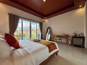 Une chambre d’hôtel avec un grand lit, un bureau, un miroir et une vue sur une piscine.