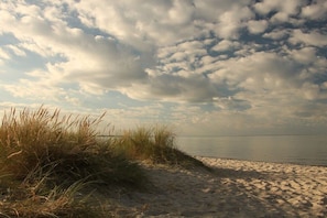 A beach with sand and grass, under a cloudy sky. - Holiday home in Pommerby with swimming pool (Pommerby)