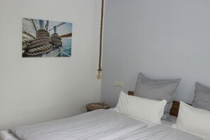 A bedroom with a bed, pillows, a bedside table, a wall-mounted light, and a framed picture of ropes. - Holiday home in Pommerby with swimming pool (Pommerby)