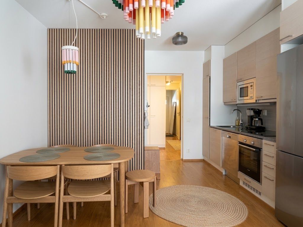 Una cocina moderna con comedor, que incluye una mesa redonda de madera, sillas y un separador a rayas.