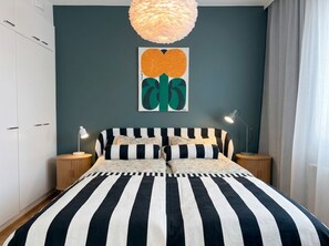 A bedroom with a bed, two bedside tables, a hanging light fixture, and a wall art piece. - Stylish 1BR Apt with Prime Location (Helsinki)