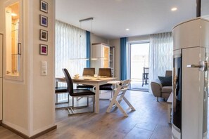A modern interior with a dining area, a sofa, and a kitchen unit. - Holiday home with 2 bedrooms (Kellenhusen)