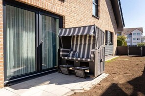 A patio with a cushioned seating area, a small table, and a grill. - Holiday home with 2 bedrooms (Kellenhusen)