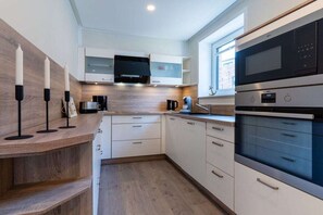 A modern kitchen with built-in appliances, a wooden countertop, and a window providing natural light. - Holiday home with 2 bedrooms (Kellenhusen)