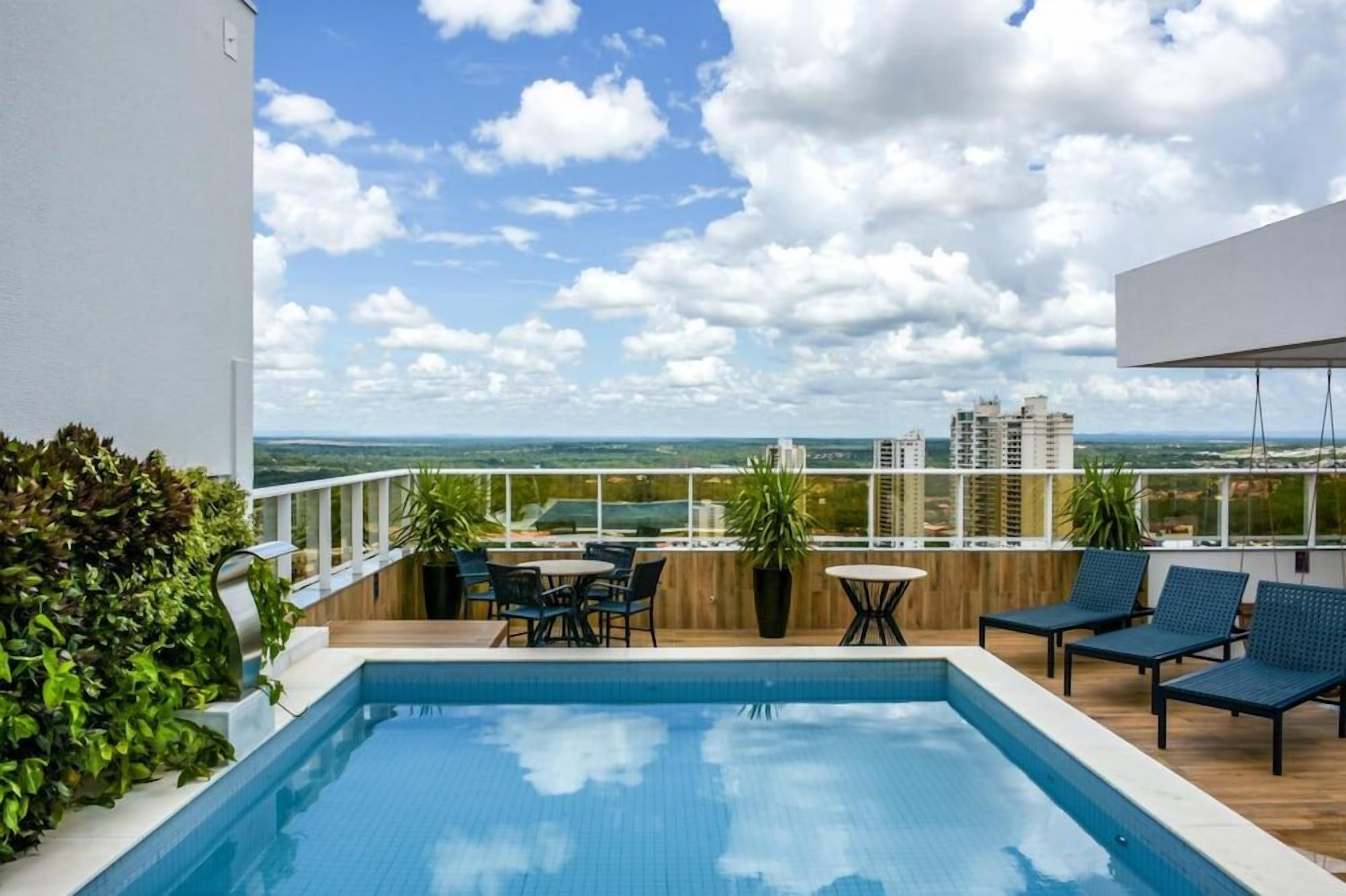 Área de piscina no terraço com vista desobstruída da linha do horizonte da cidade, espaço para sentar ao ar livre e um deck de madeira.